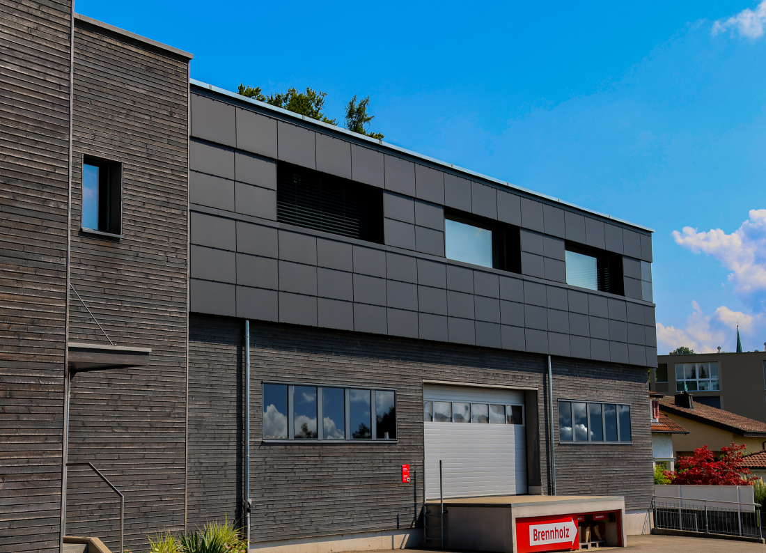 Moderne Solaranlage mit Photovoltaikmodulen an Fassade eines Gewerbegebäudes im Aargau, Schweiz