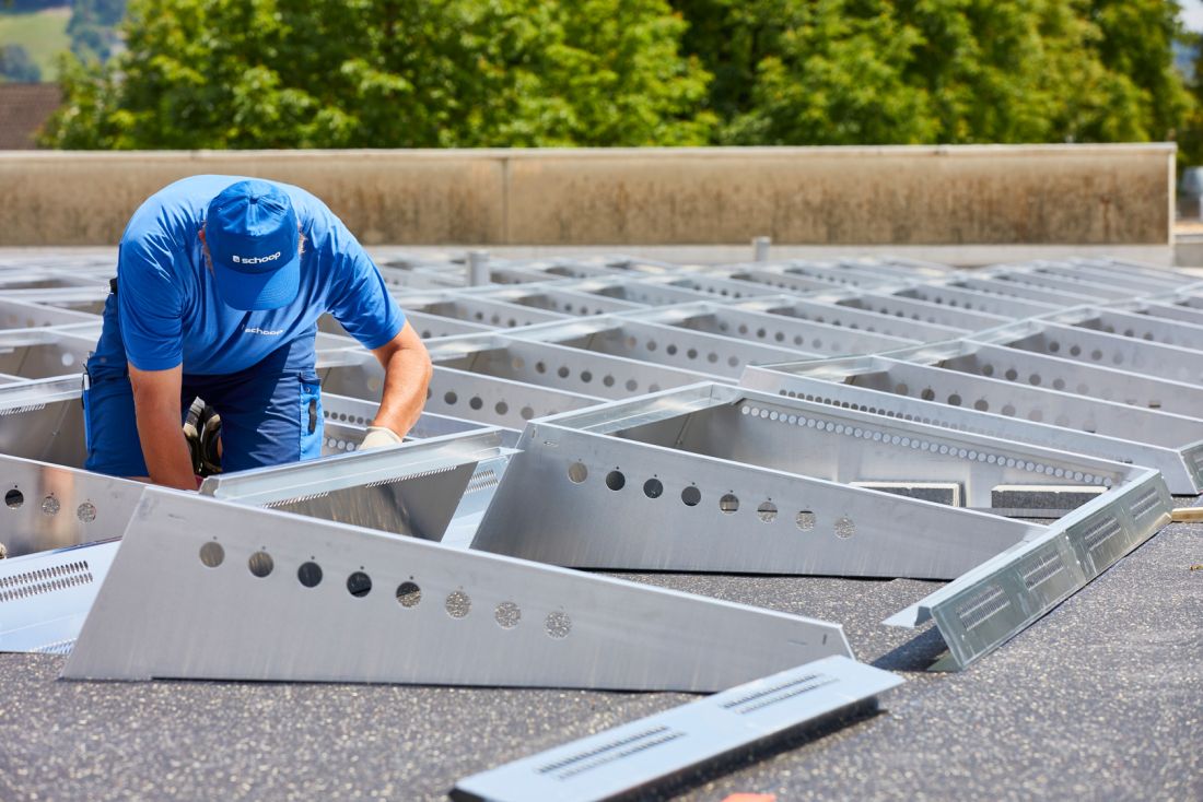 Montagearbeiter installiert Aluminium-Unterkonstruktion für Photovoltaik-Solaranlage im Aargau, Schweiz